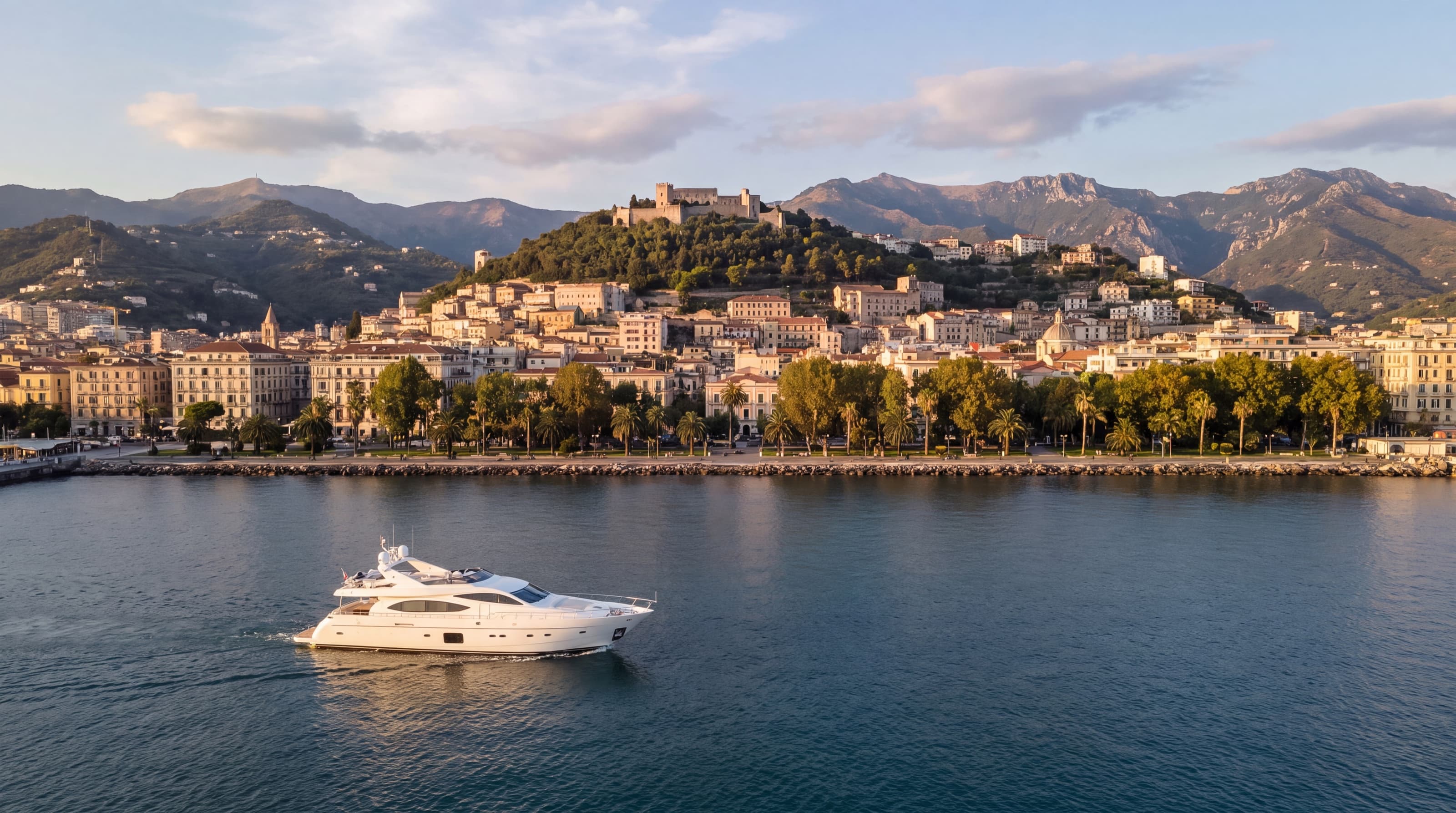 Salerno seen from the sea, with the seafront, the old town and the Arechi Castle on the hill, and a private yacht cruising