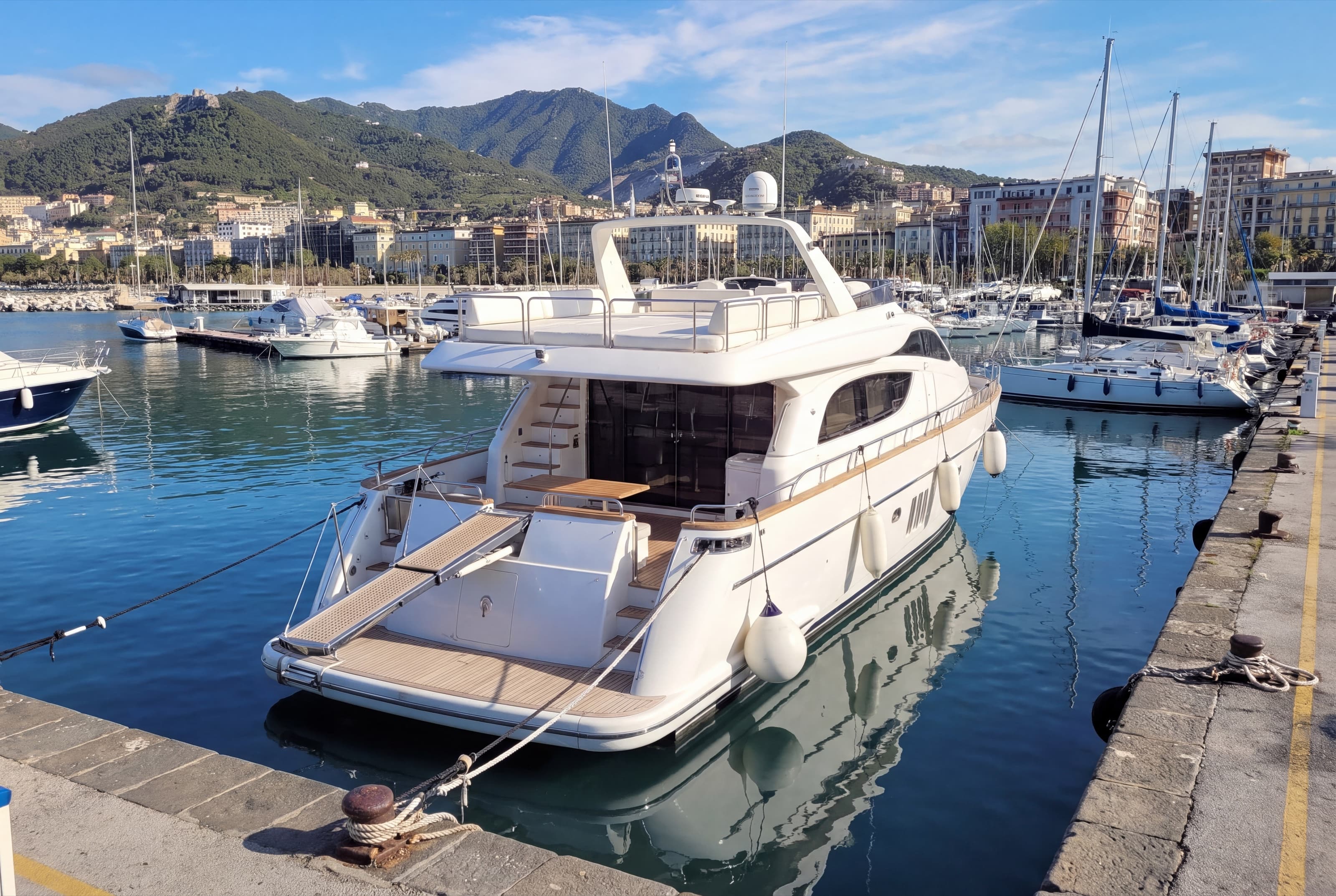 A private motor yacht moored stern-to in a marina of Salerno, ready for guests