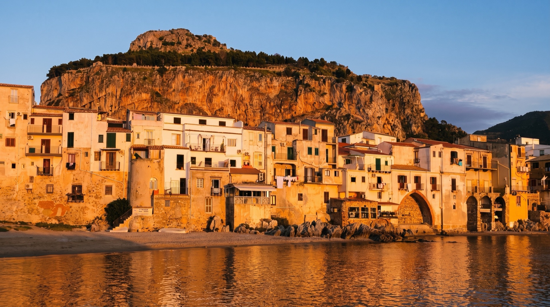 The pebble beach at Cefalù with the old town and its rooftops rising behind the shoreline