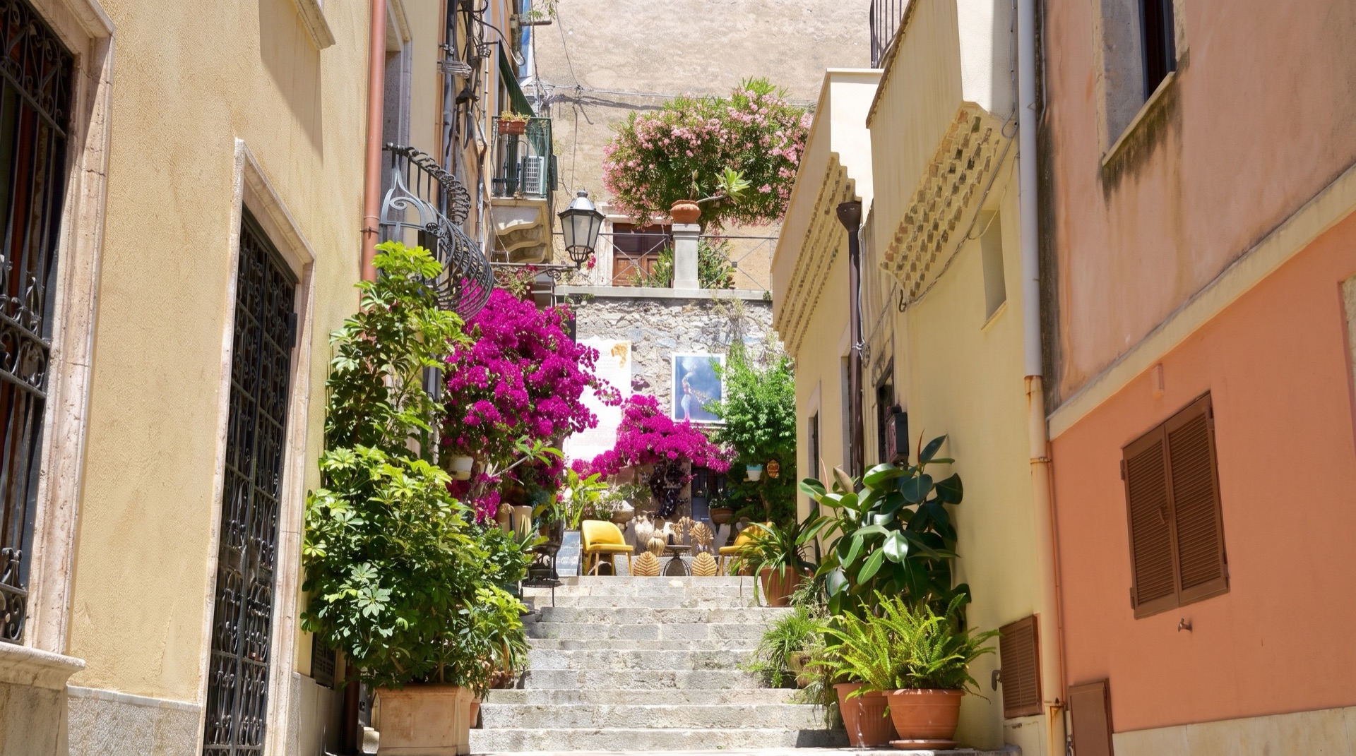 Narrow lane in Taormina's old town draped with bougainvillea in bloom